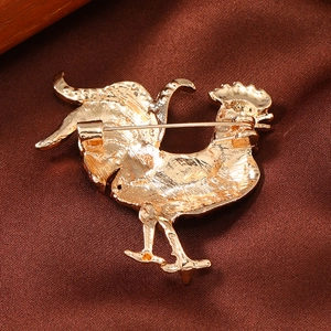 Macro view of the gold rooster brooch back showing the secure pin clasp and metal texture