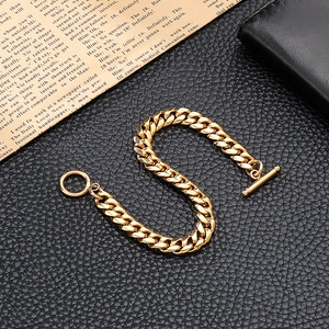 Polished gold Cuban link bracelet with OT toggle clasp on a black textured background