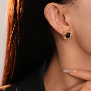Boucles d'oreilles fleur vintage en or avec pierre noire et perles sur mannequin