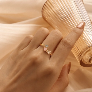 Detail of S925 silver ring featuring pink hearts and blue floral charms on a gold band