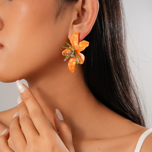 Close-up of vibrant orange resin flower earrings with beaded centers worn by a model