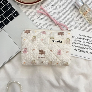 Detail of floral quilted cotton pouch with cute animal patterns and a pink zipper pull