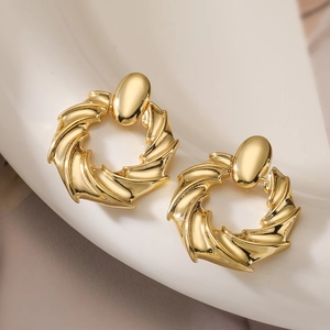 Detailed macro view of gold-plated geometric hoop earrings with vintage swirl texture