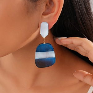 Close-up of geometric acetate earrings with blue and white stripes worn by a model