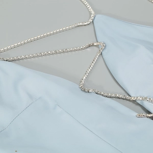 Detail of light blue satin jumpsuit featuring sparkling rhinestone chain straps and texture