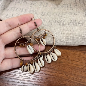 Detail of bohemian drop earrings with white seashells and brown beads on copper rings