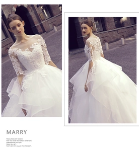 Detailed view of lace embroidery, mesh neckline and lace-up back of a white wedding dress