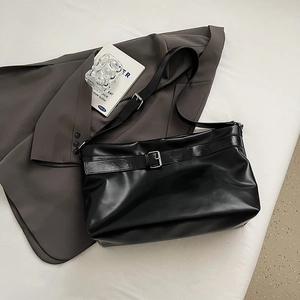 Vue à plat d'un grand sac cabas en similicuir noir avec boucle en métal et large bandoulière