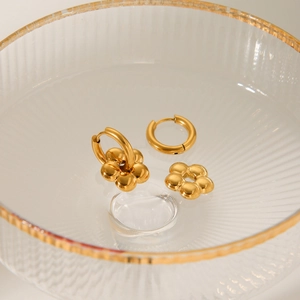 Close-up of detachable 18K gold-plated flower charms on polished hoop earrings