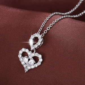 Elegant silver titanium heart necklace with shimmering zircon crystals on a dark background