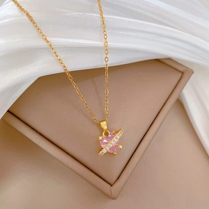 Close-up of pink heart pendant necklace with crystal bar on a beige jewelry display box