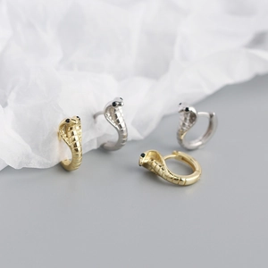 Detailed view of snake earrings in gold and silver finish with black gemstone eyes