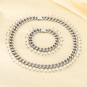 Detail of silver Cuban chain set with pearl pendants on a beige silk background