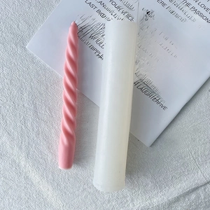 Detail view of pink spiral candle with its white cylindrical silicone mold on a book