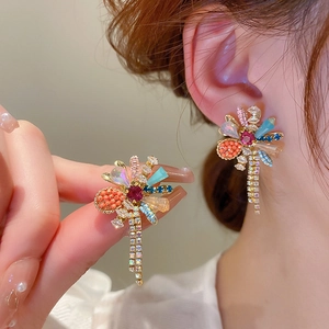 Nahaufnahme bunter Blumen-Ohrringe mit glitzernden Quasten und goldenem Metallgestell