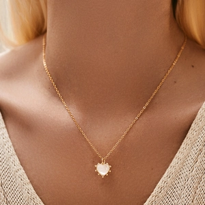 Elegant 18K gold necklace with heart shell pendant worn by a model in soft light