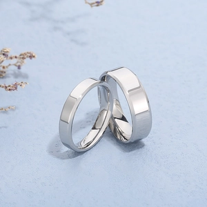 Close-up of a pair of polished silver stainless steel rings on a light blue background