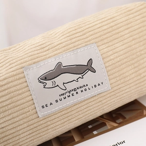 Close-up of beige corduroy pencil case featuring a cute shark embroidery patch detail