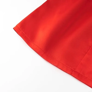 Detailed close-up of smooth red fabric texture and neat stitching on dress hemline