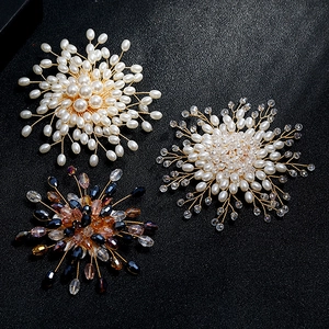 Three handmade wire-wrapped snowflake brooches with pearls and crystals on black background