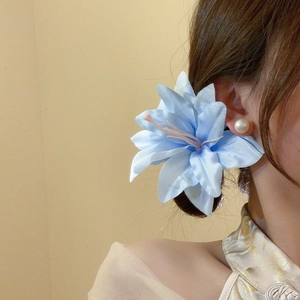 Detailed view of light blue fabric lily hair clip worn on model with silk finish texture