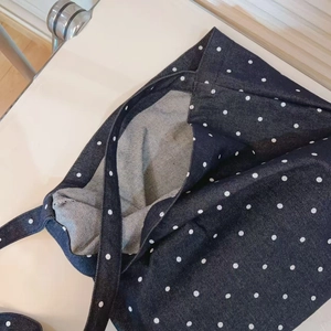 Detail of blue denim tote bag with white polka dots and spacious interior texture