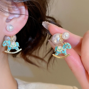 Detail of light blue enamel rocking horse earrings with pearls and gold plating