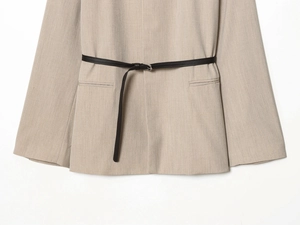 Close-up of beige woven blazer fabric featuring a slim black leather waist belt