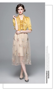 Detail of yellow ruffled collar top and beige mesh midi skirt with butterfly embroidery