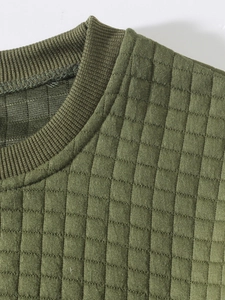 Detail of army green quilted texture fabric and ribbed crewneck on men's sweater