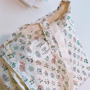 Detailed macro view of floral cotton tote bag with vintage botanical print and woven label