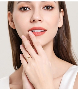 Close-up of a minimalist gold ring with a single moissanite stone worn by a model