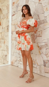Détail de robe fleurie avec col en V ajouré et manches bouffantes courtes en orange