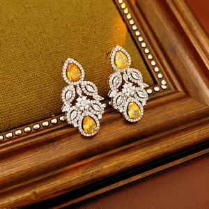 Detail of drop-shaped zircon flower earrings set against a textured dark background