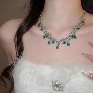 Detail of silver necklace with green gemstone teardrop pendant in floral leaf design