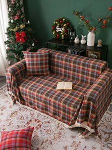 Detail of red plaid sofa cover with cream tassels and thick woven fabric texture