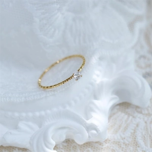 Close-up of thin 18k gold plated titanium ring with twisted texture and single zircon