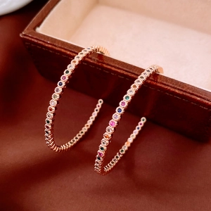 Détail de créoles en or rose serties de pierres multicolores sur boîte en cuir