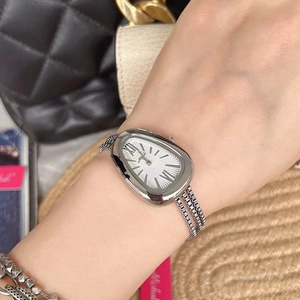Macro shot of silver snake-head watch with multi-strand chain strap on wrist