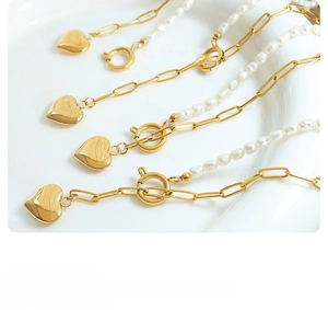 Detail of four golden paperclip necklaces with fresh water pearls and heart pendants