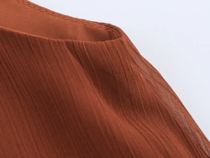 Detaillierte Makroansicht der plissierten Chiffon-Struktur und der Naht am Halsausschnitt