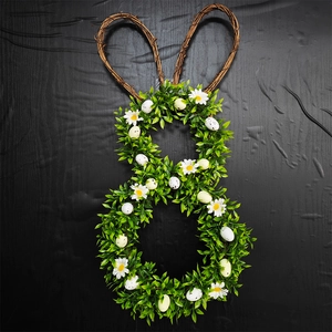 Macro detail of Easter bunny wreath with green leaves, daisies and speckled eggs