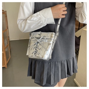 Détail d'un sac seau argenté avec ruban de nœud papillon sur fond de chemise blanche