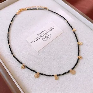 French vintage beaded necklace with black beads and gold round pendants on a tray