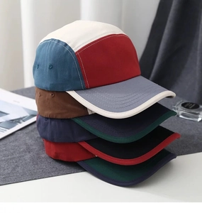 Detailed stack of multi-color block five-panel baseball caps with metal ventilation eyelets