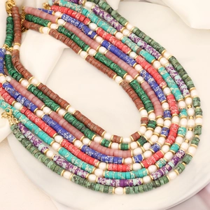 Detailed macro view of multi-strand natural stone and pearl necklace with golden clasp