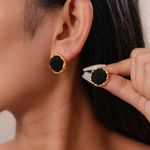 Close-up of elegant gold irregular wavy earrings with black flocked center on model