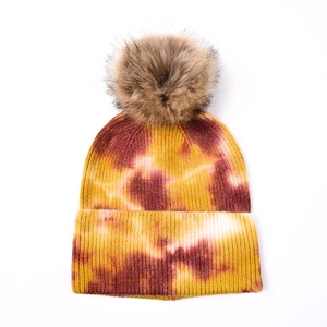 Détail du bonnet en maille tie-dye avec texture côtelée et pompon en fausse fourrure