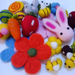 Macro shot of assorted handmade wool felt charms including bees, carrots and flowers