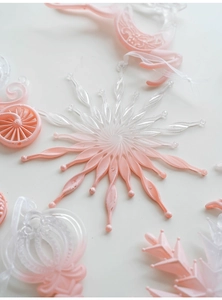 Close-up of pink and transparent star, pumpkin carriage, and snowflake holiday ornaments